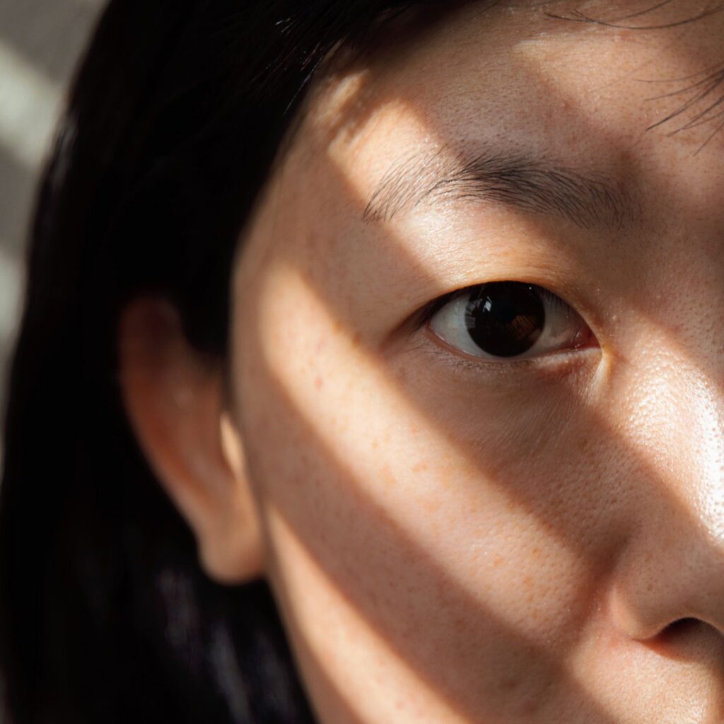 Close-up of a woman's eye in soft sunlight, highlighting the eyelid and under-eye area