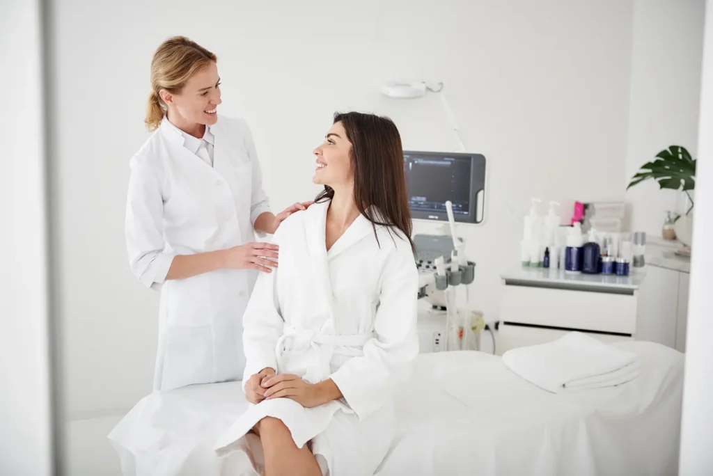 Woman in a white robe talking with a clinician in a bright treatment room