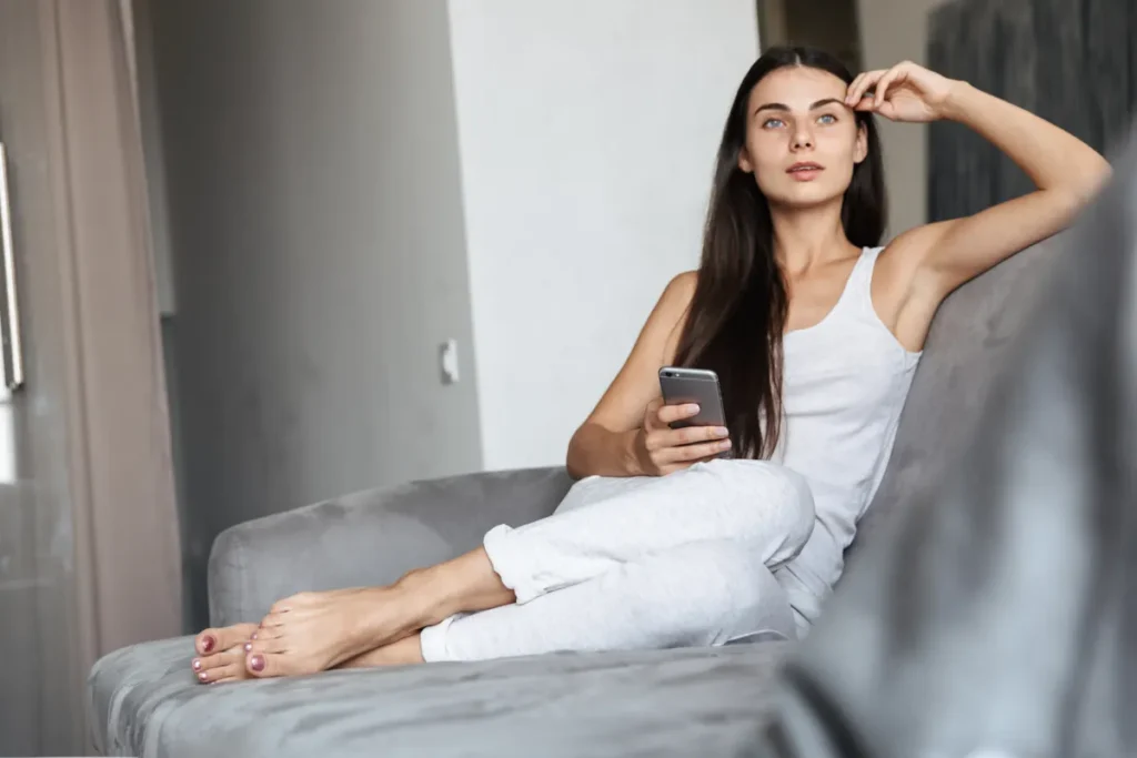 Woman in a tank top relaxing on a couch at home