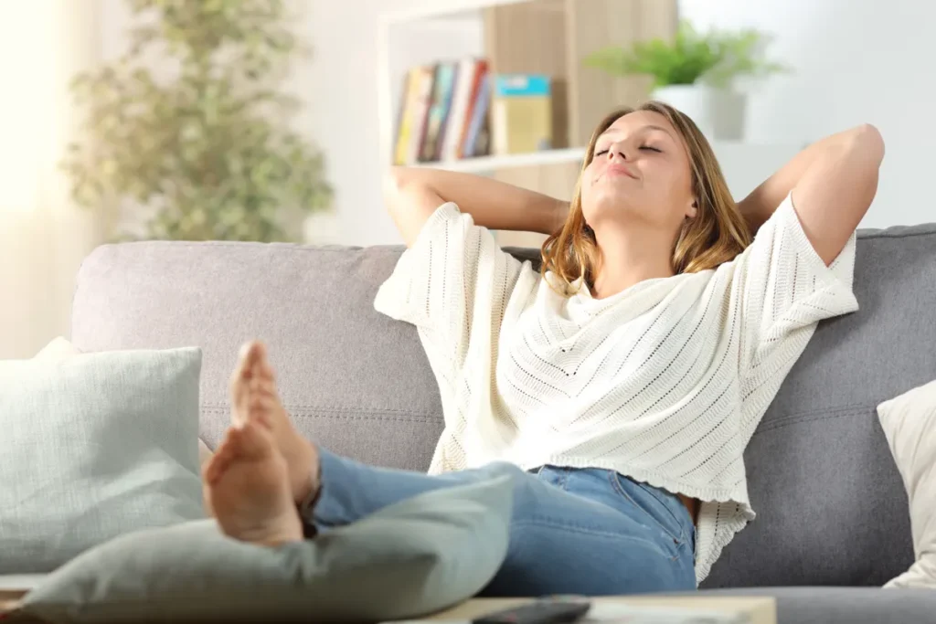 Woman relaxing barefoot on a sofa with her eyes closed