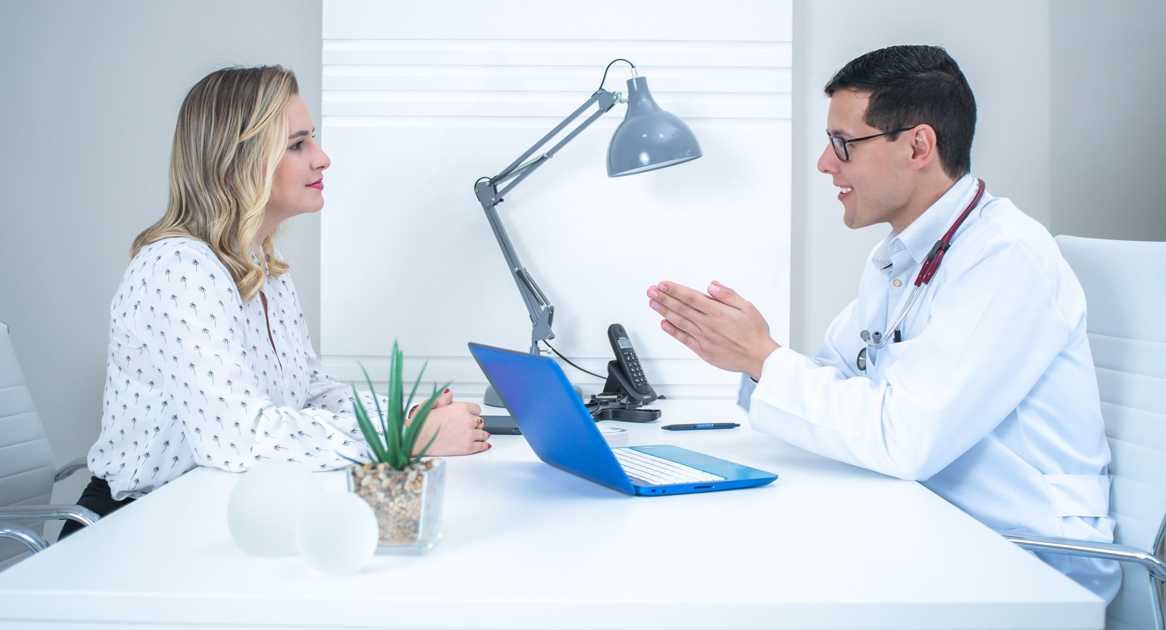 Cosmetic surgeon discussing tummy tuck options with a patient during a consultation in a bright Newport Beach clinic