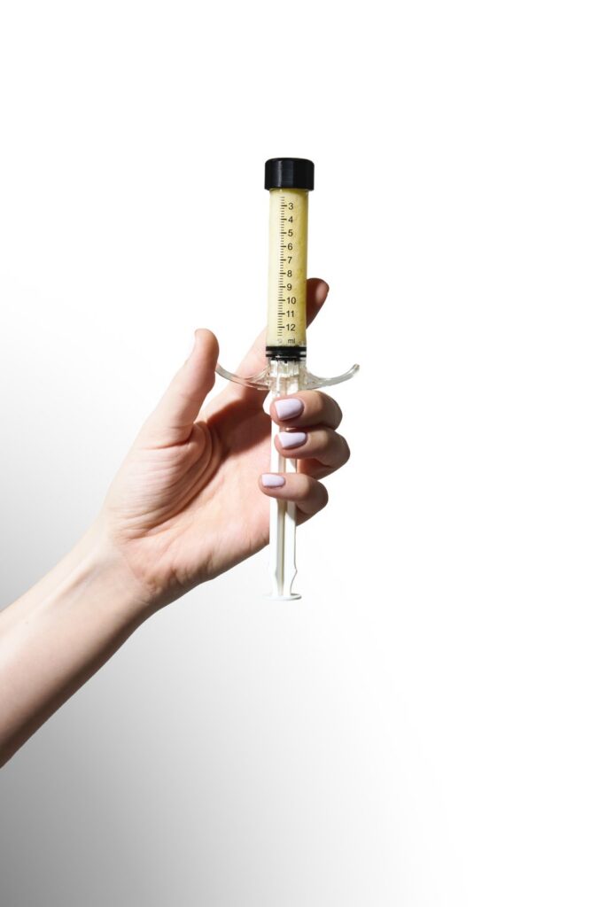 Hand holding a prefilled alloClae structural adipose tissue container