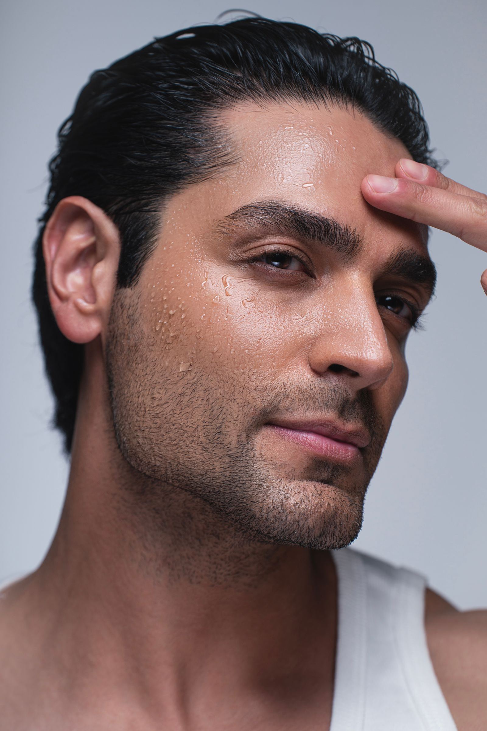 Man in his 30s with smooth, hydrated skin touching his forehead, illustrating Botox for men in Newport Beach