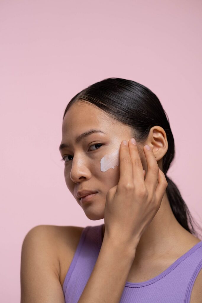 A young woman touching her cheek where she has just applied a skincare cream, illustrating gentle moisturizer and aftercare