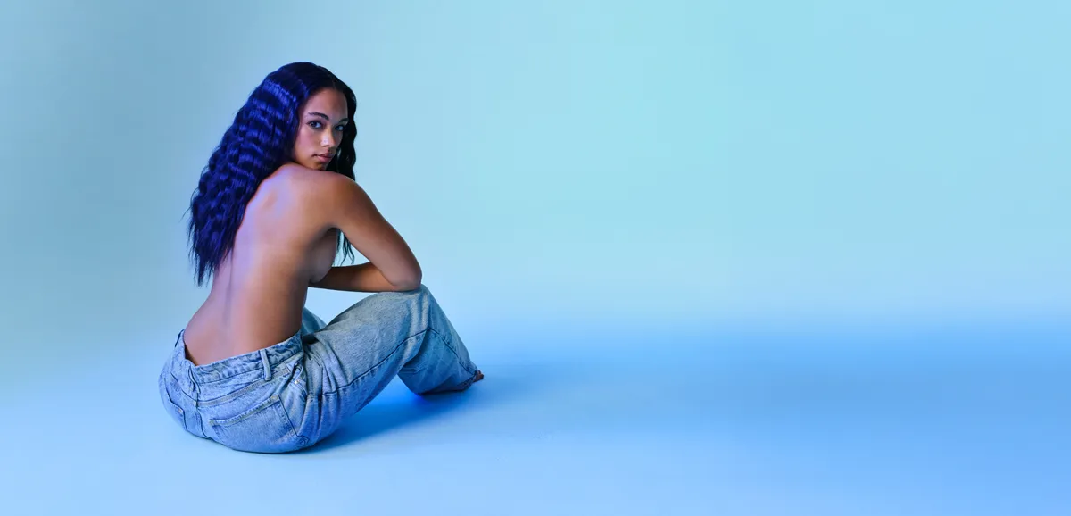 Model seated against a blue background, Renuvion skin tightening